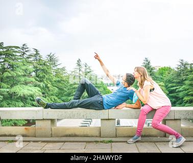 Un jeune couple espiègle qui se détourne de joie avec un masque masculin qui montre son doigt vers le haut.Image d'arrière-plan d'espace vide du côté supérieur. Banque D'Images