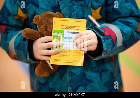 15 décembre 2021, Basse-Saxe, Lüneburg: Une fille tient un animal en peluche, sa carte de vaccination et sa carte d'assurance maladie dans la zone d'attente d'un centre mobile de vaccination pour enfants.La vaccination de Corona pour les enfants de cinq à onze ans a commencé en Basse-Saxe.Photo: Daniel Reinhardt/dpa Banque D'Images