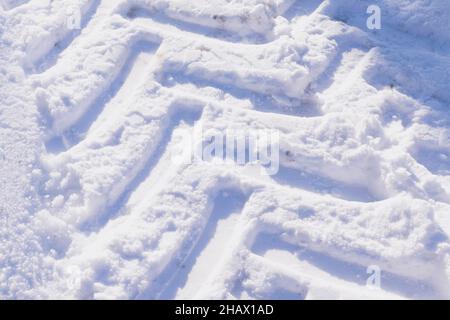 Marque de pneu à neige d'un tracteur.Route enneigée.Concept de conditions routières dangereuses, hiver, sécurité sur les routes, conduite extrême.Copier l'espace. Banque D'Images