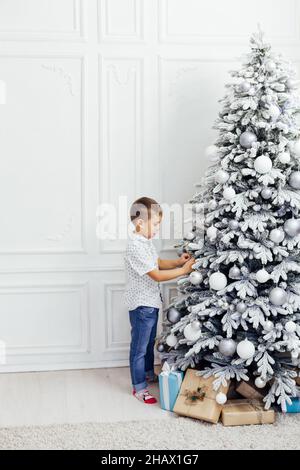 Garçon décorera arbre de Noël nouvel an cadeaux de vacances Banque D'Images