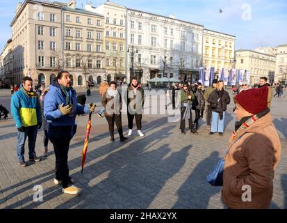 Cracovie.Cracovie.Pologne.Guide tenant un parapluie aux couleurs du drapeau espagnol parlant à un groupe de touristes espagnols sur la place du marché principal. Banque D'Images