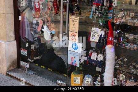 Cracovie.Cracovie.Pologne.jeune femme assistant de magasin portant masque nettoie la fenêtre avant de magasin. Banque D'Images