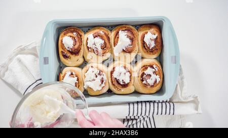 Pose à plat. Glacer des petits pains à la cannelle fraîchement cuits dans une casserole bleue. Banque D'Images