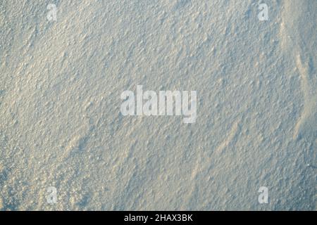 Texture inégale de la neige dans la lumière du coucher du soleil. Banque D'Images