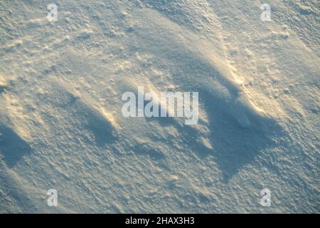 Texture inégale de la neige dans la lumière du coucher du soleil. Banque D'Images