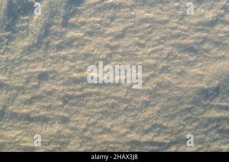 Texture inégale de la neige dans la lumière du coucher du soleil. Banque D'Images