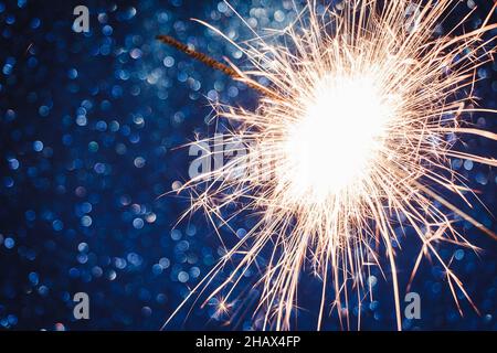 Brillant sur fond bleu.Fêtez le nouvel an et Noël.Étincelles brillantes de feu et de bokeh.Mise au point sélective Banque D'Images