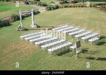 Magnifique cadre extérieur pour la cérémonie de mariage avec chaises argentées et blanches Banque D'Images