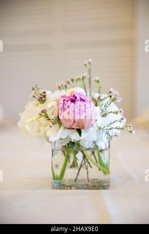 Œillets blancs et fleurs de pivoine rose dans un petit pot en verre Banque D'Images