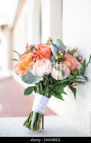 Fleurs roses, jaunes et orange bouquet de mariée appuyé sur le mur de ciment Banque D'Images