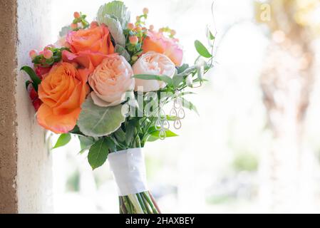 Fleurs roses, jaunes et orange bouquet de mariée appuyé sur le mur de ciment Banque D'Images