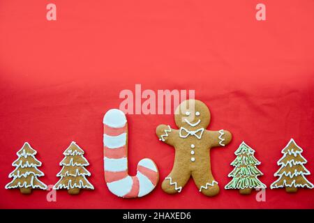 Biscuits de Noël faits main de pain d'épice avec espace de copie sur fond de tissu rouge.Fond de cuisson fait maison.Carte de fête avec guichet automatique esthétique Banque D'Images