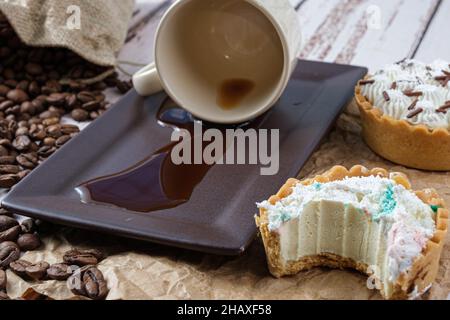Mini tarte à la pâte de beurre et ganache au chocolat blanc à côté d'une tasse de café retournée. Banque D'Images