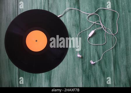 Casque blanc avec disques en fil et vinyle sur fond vert.Technique rétro pour la lecture de musique. Banque D'Images