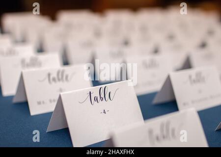 Les rangées de tables blanches pliées placent les cartes sur la table bleue de réception de mariage Banque D'Images