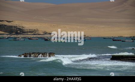 Village de pêcheurs côtier dans la baie de l'océan pacifique crique turquoise eau pérou réserve naturelle avec des dunes de sable d'argile rouge et des montagnes des andes vacances touristique Banque D'Images