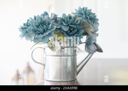 Décorations miniatures en étain argenté avec fleurs en soie bleu pâle à l'intérieur sur une table en bois Banque D'Images