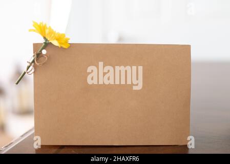 Boîte en carton brun vierge avec fleur jaune attachée au coin Banque D'Images