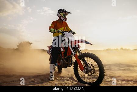 Pilote de motocross sur le moteur de sport au-dessus de la poussière paysage Banque D'Images