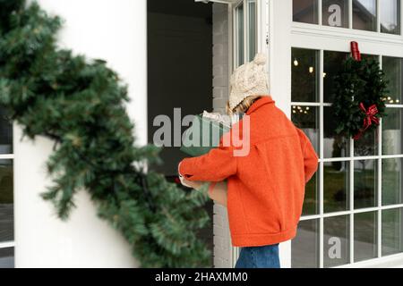 Femme portant des cadeaux de Noël emballés marchant dans une maison Banque D'Images