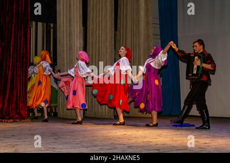 Omsk, Russie.05 décembre 2021.Un joueur de Bayan et quatre danseuses finissant la danse de Prohodka.Performance de l'ensemble Samotsvety. Banque D'Images