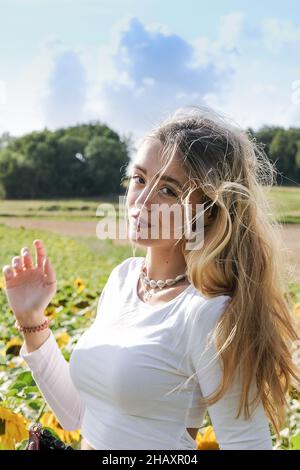 Portrait d'une belle fille balayée par le vent debout dans un champ de tournesol en été, France Banque D'Images