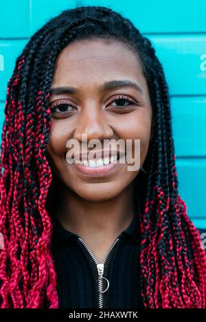 Jeune contenu noir femme avec des tresses afro regardant la caméra sur fond bleu Banque D'Images