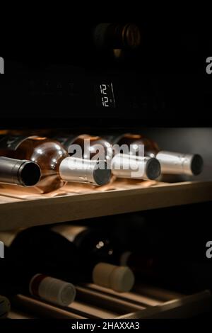 Assortiment de bouteilles d'alcool placées sur des étagères dans le réfrigérateur à vin en maintenant une température constante Banque D'Images