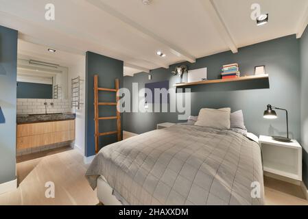 Intérieur de chambre moderne pour les jeunes étudiants avec lit table de chevet avec lampe étagère et salle de bains Banque D'Images