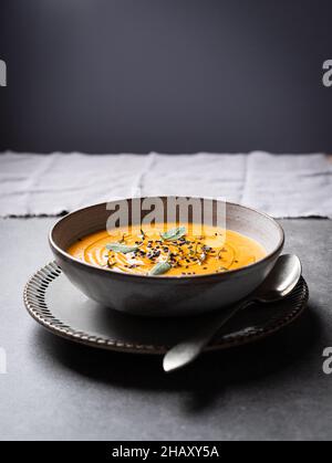 Bol avec une délicieuse soupe de potiron servie avec des assaisonnements placés sur une table grise dans le restaurant Banque D'Images