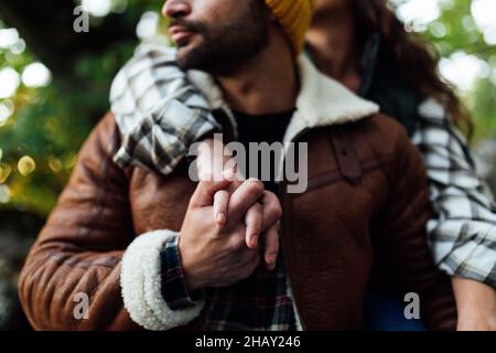 Crop anonyme couple romantique de touristes en chaud tenant les mains tout en passant du temps ensemble dans la nature sur un arrière-plan flou Banque D'Images