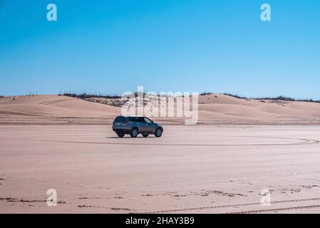 Voiture hors-bord traversant des dunes de sable à la plage par beau temps ensoleillé Banque D'Images