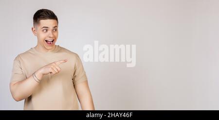 L'homme pointe vers le côté et sourit.Photo de jeune attrayant excité beau moderne indépendant, entrepreneur, étudiant employeur regardant la caméra Banque D'Images