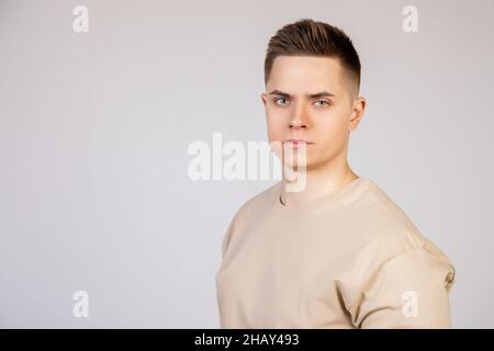 Beau jeune homme avec une coiffure élégante regardant l'appareil photo avec une expression sérieuse.Photo de jeune sympathique freelance moderne Banque D'Images