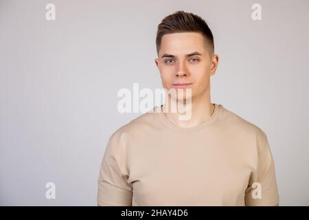 Beau jeune homme avec une coiffure élégante regardant l'appareil photo avec une expression sérieuse.Photo de jeune sympathique freelance moderne Banque D'Images