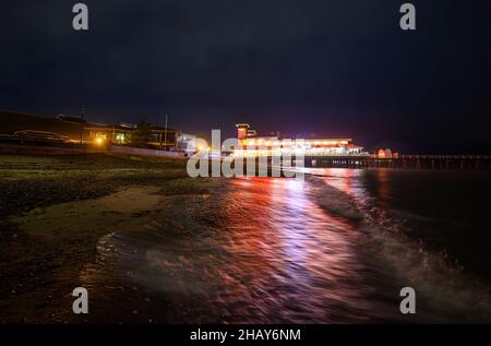 Felixstowe, Suffolk, Royaume-Uni: Jetée de Felixstowe la nuit illuminée de feux rouges et jaunes.Vue sur la jetée depuis la plage avec des reflets dans la mer. Banque D'Images