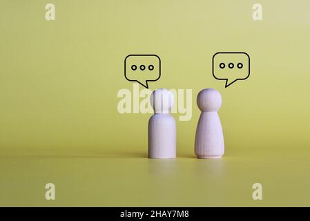 Poupées en bois avec bulle de message vocal et chat sur fond jaune avec espace de copie.Concept d'interaction et de chat sur les réseaux sociaux. Banque D'Images