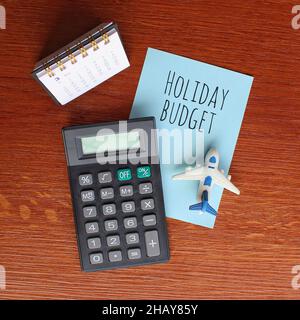 Planification et concept financier.Vue de dessus du calendrier de bureau, de la calculatrice, de l'avion jouet et du papier avec texte BUDGET DE VACANCES Banque D'Images