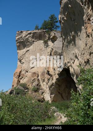 Un sentier non pavé menant à une colline jusqu'à l'entrée d'une grotte dans le parc national de Pictograph Cave près de Billings, Montana avec une végétation en premier plan. Banque D'Images