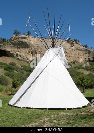 Tipi ou tipi en toile blanche dans un champ du parc national de Pictograph Cave près de Billings, Montana, avec une falaise de grès et une grotte en arrière-plan et une cadee Banque D'Images