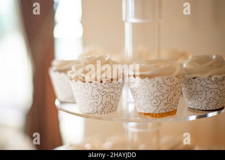 cupcakes vanille dans des tasses en dentelle blanche sur la tour à gâteau Banque D'Images