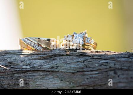 Anneaux de mariage en or avec des diamants carrés côte à côte sur bois en plein air Banque D'Images