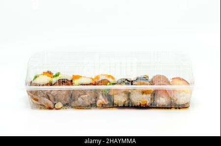 Gros plan de divers types de sushi dans une boîte à emporter, une boîte à aliments de livraison en forme longue, vue de face sushi dans un emballage vide sur le dos blanc Banque D'Images
