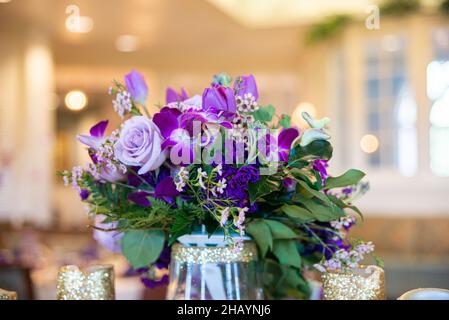 Table à bouquet de fleurs et roses violettes au centre de la réception de mariage. Banque D'Images