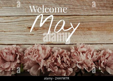 Bienvenue mai texte typographique avec bouquet de fleurs roses sur fond de bois Banque D'Images