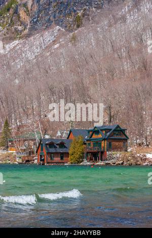 Une maison unifamiliale au bord de l'eau sur le lac Willoughby. Mont Pisgah pente raide et falaises abruptes à l'arrière. Eaux du lac Emerald. Westmore, Vermont Banque D'Images