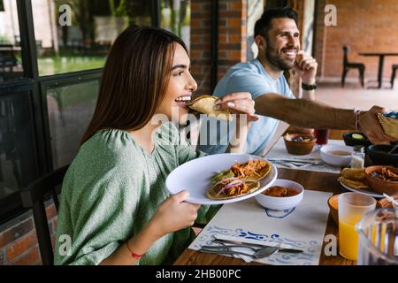 Jeune femme latine mangeant des tacos mexicains sur une terrasse de restaurant au Mexique en Amérique latine, se sentant heureuse lors d'une journée d'été Banque D'Images