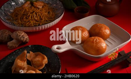 Cuisine chinoise maison avec petits pains de porc frits, boulettes frites et méine de vache ou nouilles chinoises sautées aux crevettes. Banque D'Images