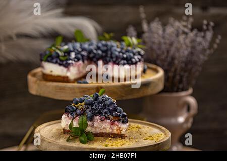 Dessert au cheesecake aux myrtilles, tranche de cheesecake triangulaire sur un présentoir à gâteaux en bois Banque D'Images