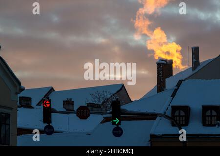 Le soleil levant illumine la fumée provenant de la cheminée en hiver Banque D'Images